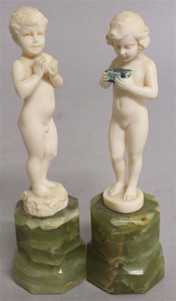 Figures of a standing nude boy and girl, the boy carrying an apple, the girl a box by Ferdinand Preiss