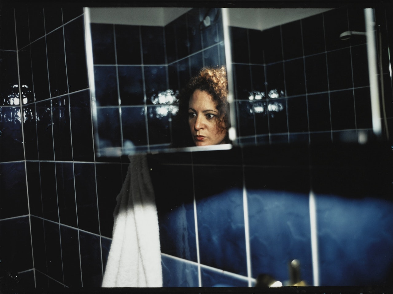 SELF PORTRAIT IN BLUE BATHROOM, BERLIN , 1992 by Nan Goldin