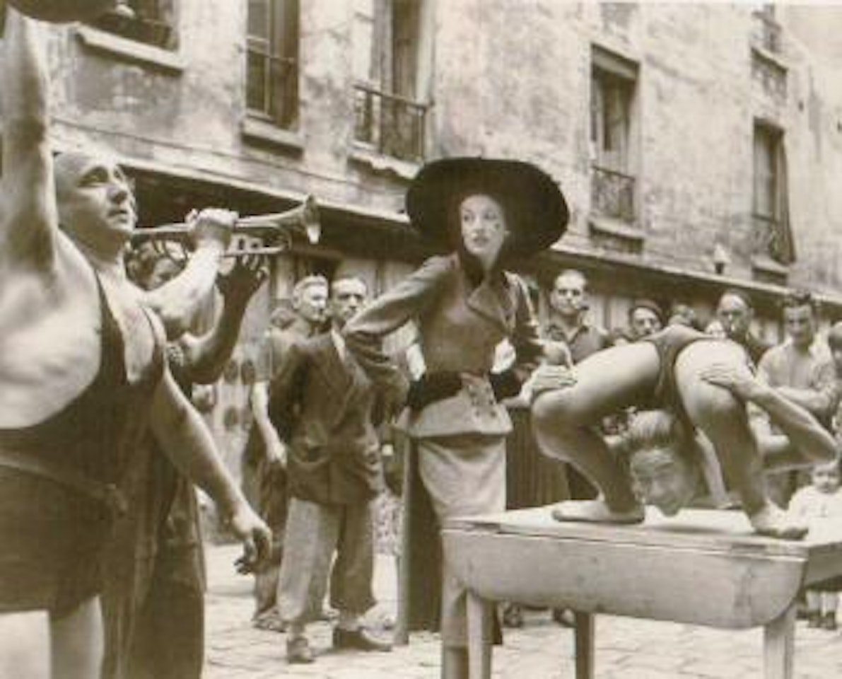 Elise Daniels with street performers, suit by Balenciaga, Le Marais, Paris by Richard Avedon