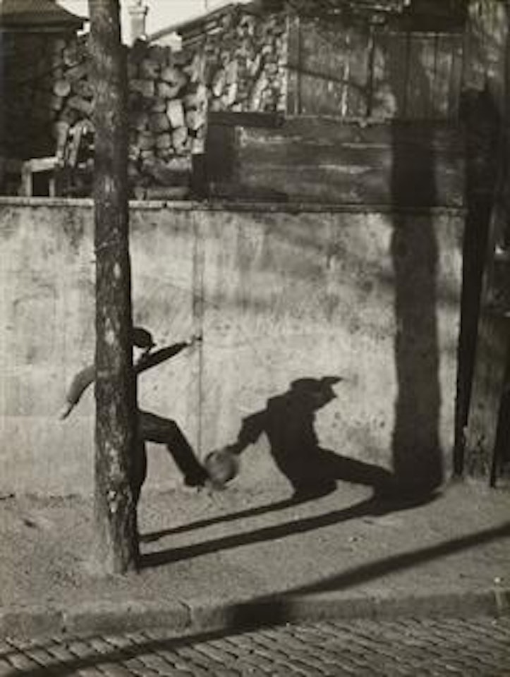 Child kicking ball by André Kertész