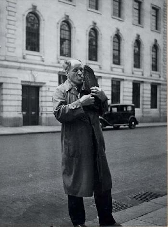 Man playing a shoulder scythar, London by Dora Maar
