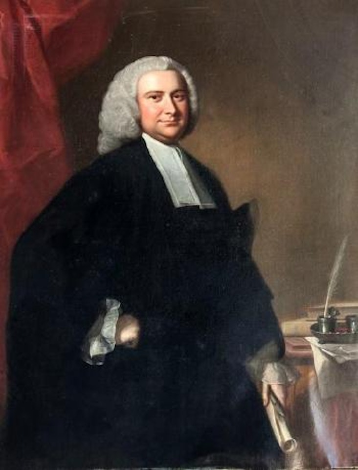 Portrait of a cleric, three quarter length, in robes, holding a scroll and beside a table with desk stand and books, before a red draped curtain by Thomas Hudson