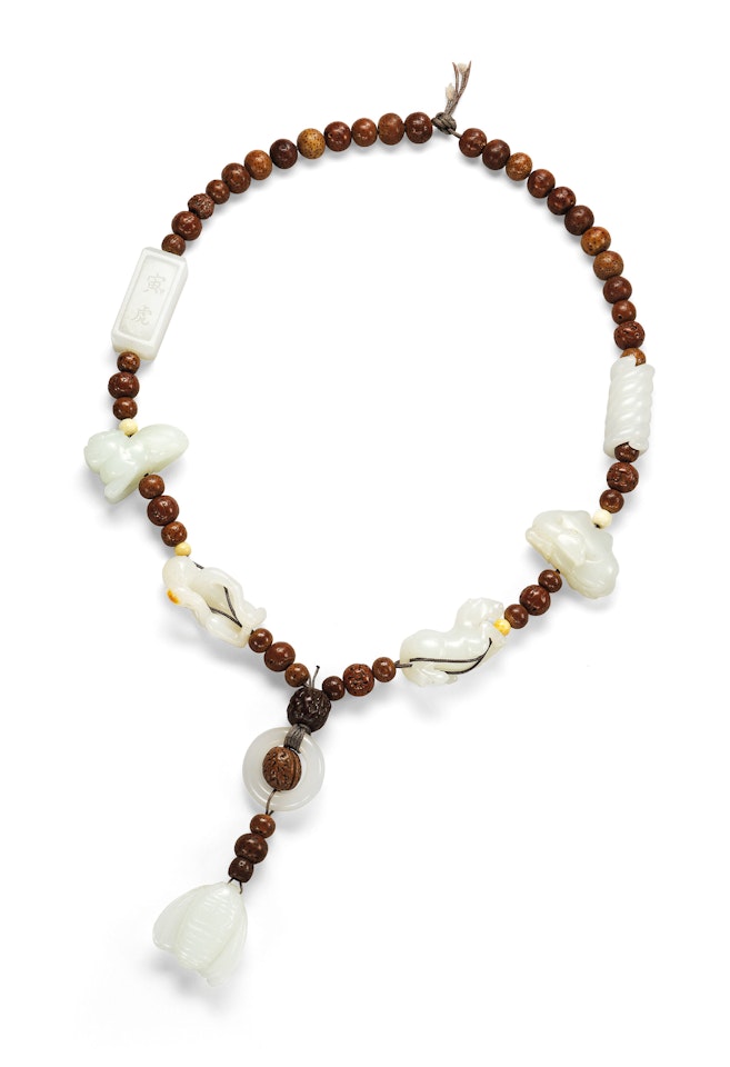 A CARVED WHITE JADE AND NUT BEAD NECKLACE by Anonymous