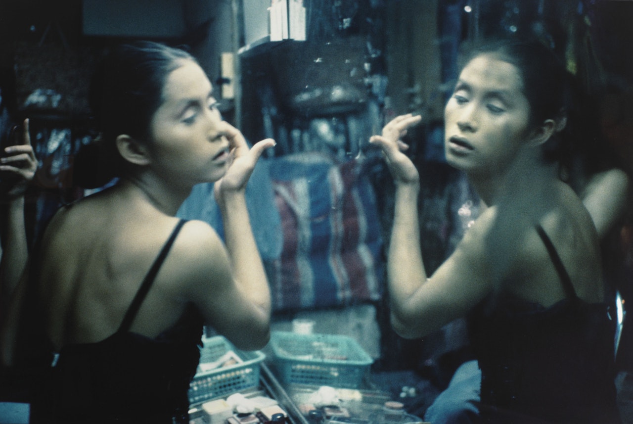 C. putting on her make-up at Second Tip, Bangkok, 1992 by Nan Goldin