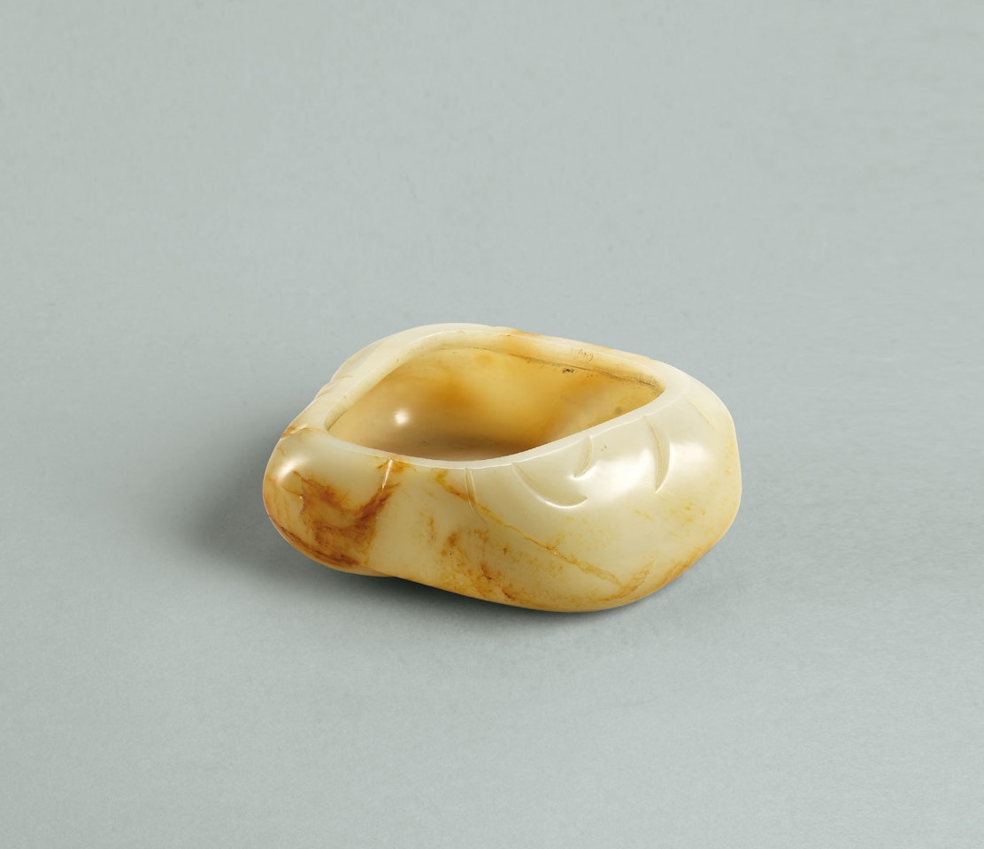 A WHITE AND RUSSET JADE PEBBLE-FORM WASHER by Anonymous