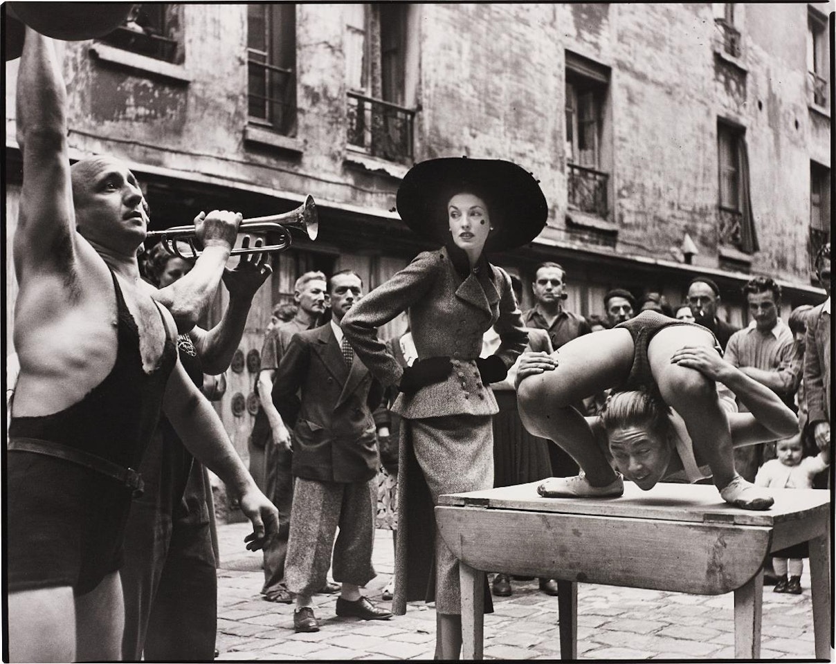 Elise Daniels with street performers, Suit by Balenciaga, Le Marais, Paris, August, 1948 by Richard Avedon