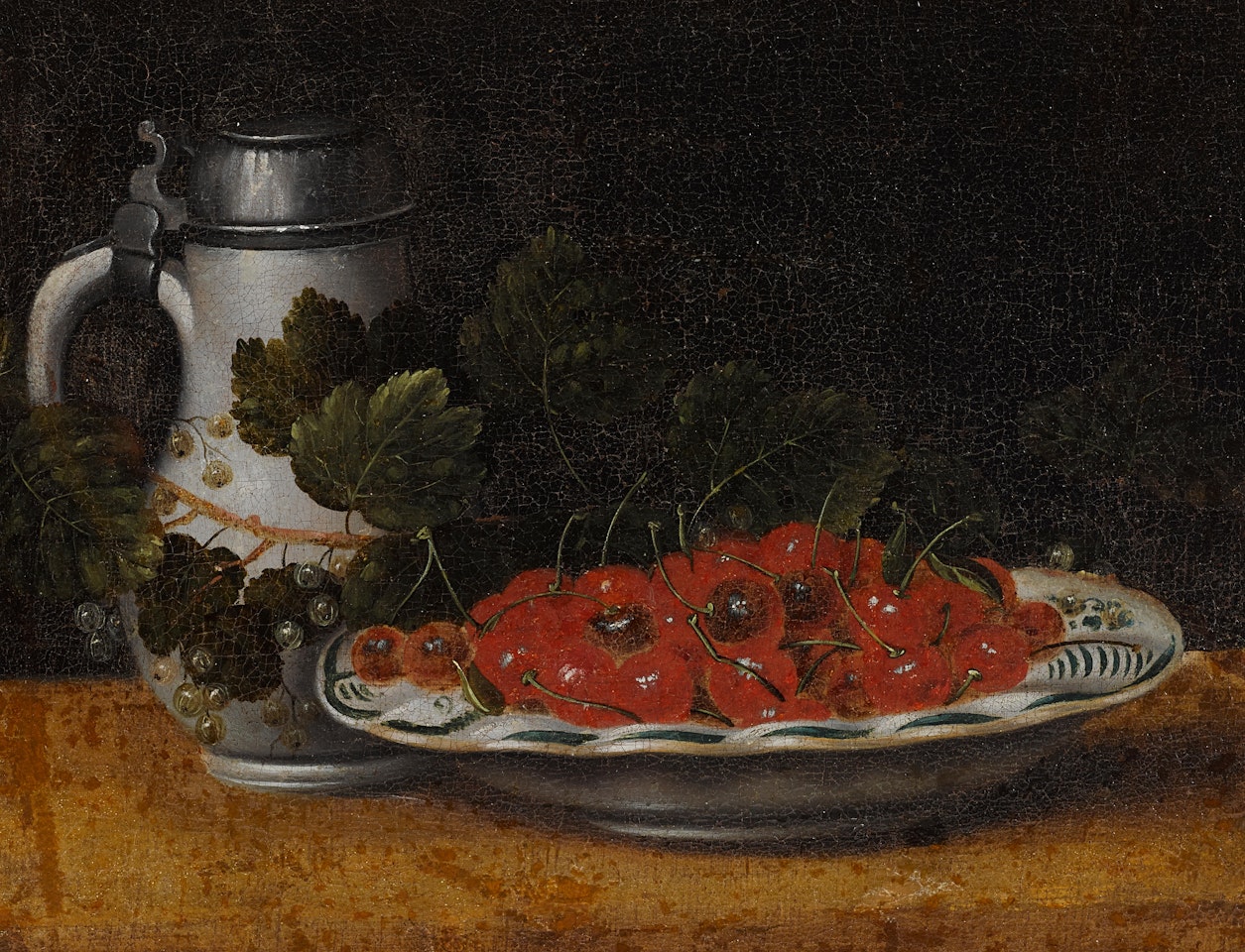 A still life with a bowl of cherries, currants, and a tankard on a table by Dutch School