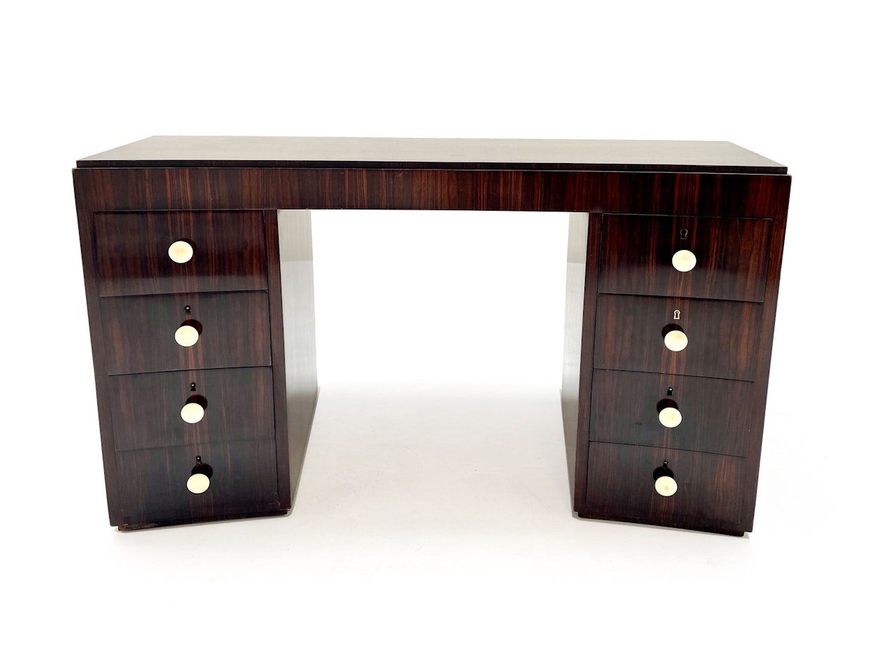 Rosewood veneer desk with curved molded top resting on two boxes opening with four drawers with Bakelite handles by Jacques Adnet
