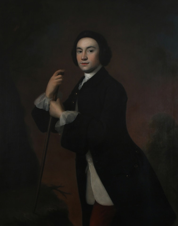 Portrait of a gentleman, three-quarter length, wearing a blue coat, white waistcoat and red trousers, leaning on a stick by English School
