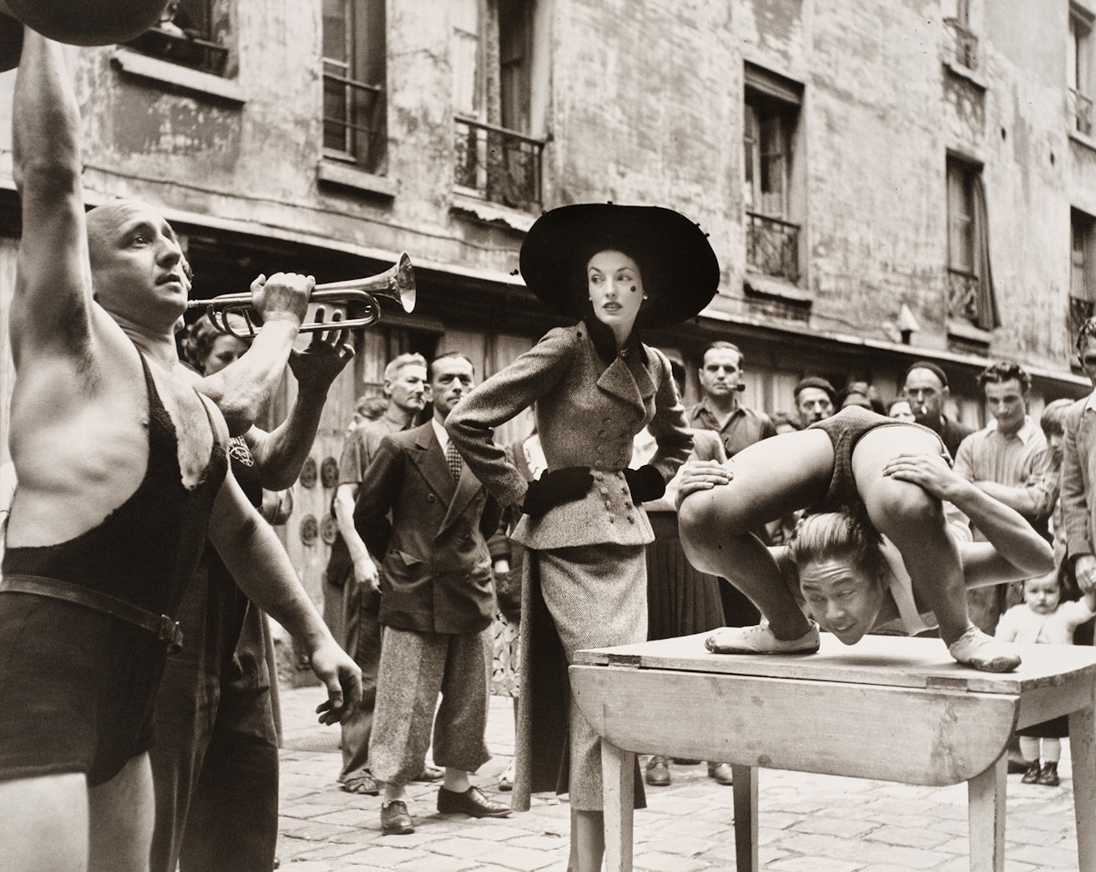 Elise Daniels with Street Performers, Suit by Balenciaga, Le Marais, Paris, August, 1948 by Richard Avedon