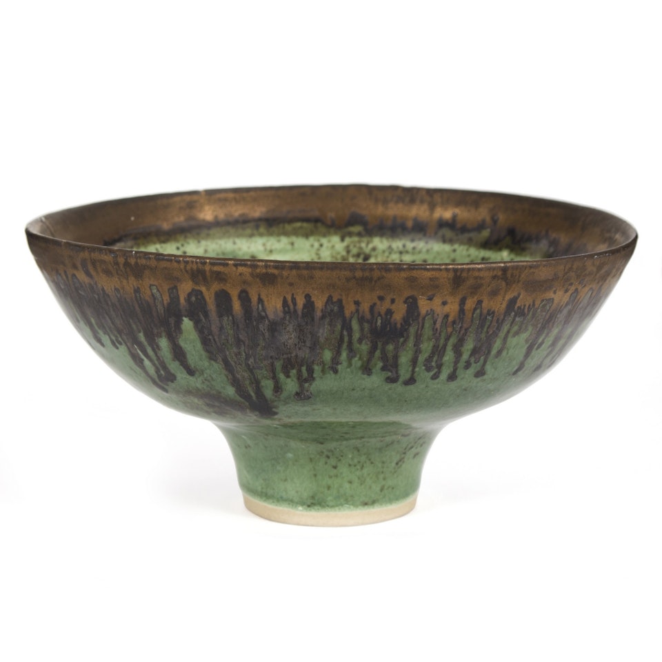a stoneware footed bowl with an emerald green glaze and bronzed manganese drip rim by Lucie Rie