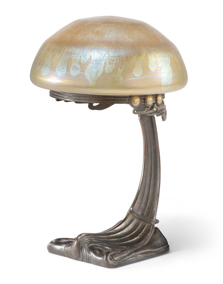 AN AUSTRIAN PATINATED BRONZE AND IRIDESCENT GLASS TABLE LAMP by Gustav Gurschner