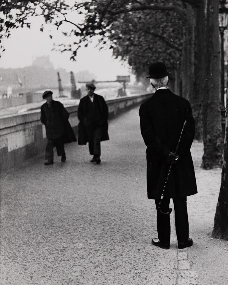 Man with walking stick, Quai d"Orsay, Paris by André Kertész